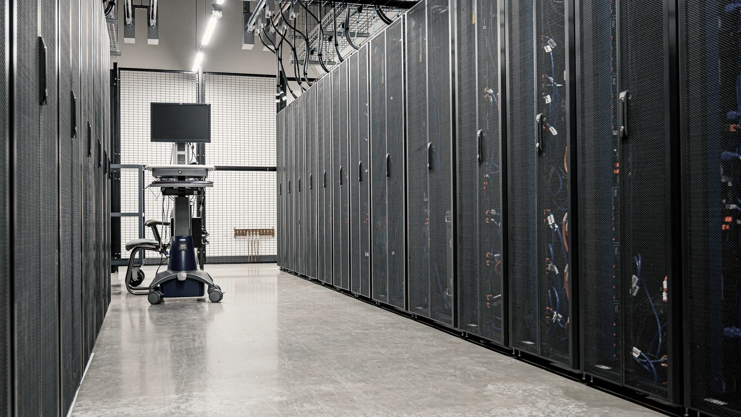 Rows of server cabinets in a data centre, seen down the aisle.